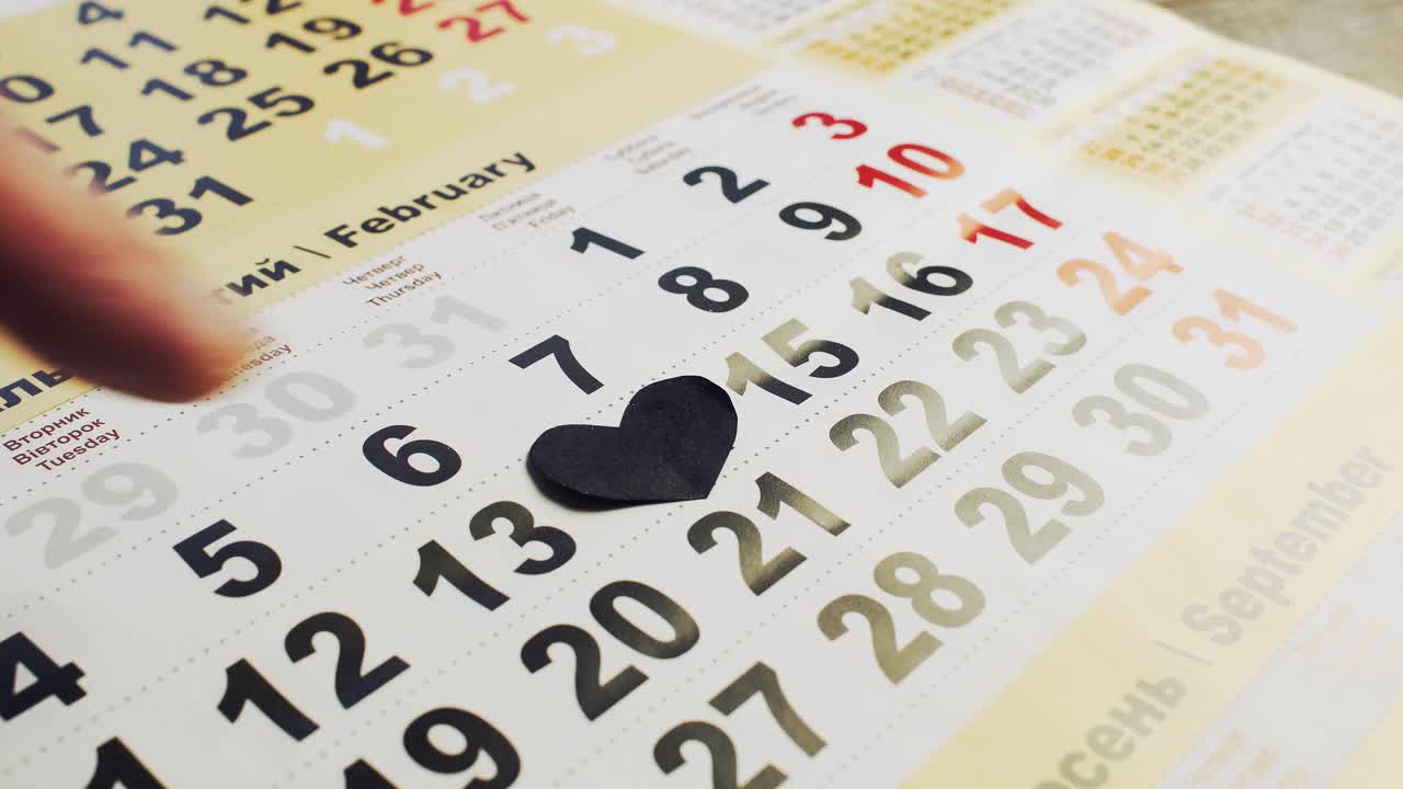 black paper heart on the 14th of february on a calendar. Love and broken heart