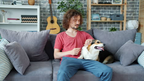 man and corgi on sofa