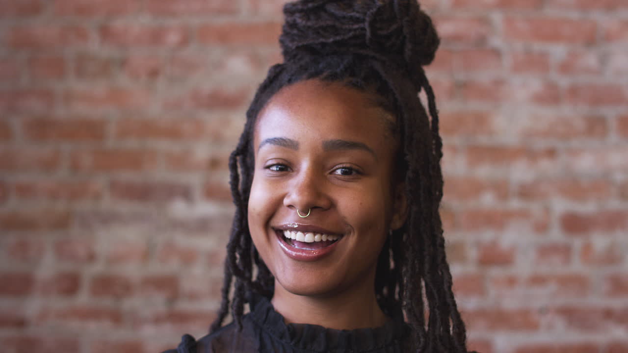 retrato de una mujer afroamericana sonriente de pie contra una pared de ladrillo en una cafetería