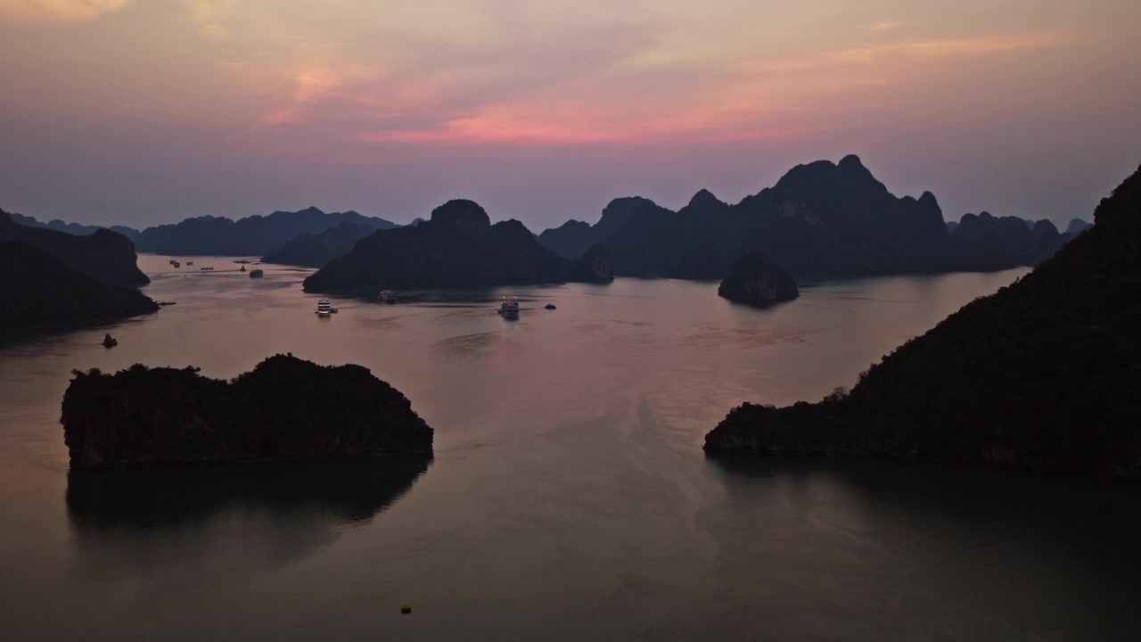 Các khối đá vôi karst và mặt nước yên bình của Vịnh Hạ Long ở Việt Nam lúc hoàng hôn - Cảnh quay drone