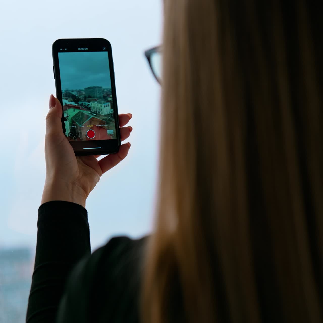 A beautiful smiling woman wearing eyeglasses is using a phone