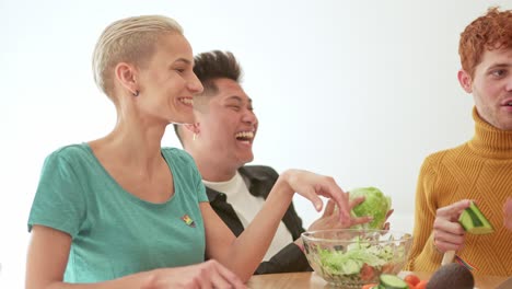 diverse group of friends laughing while preparing a healthy salad together