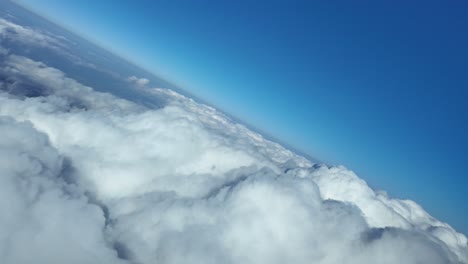 an immersive pilot’s view in a 45-degree left turn over an endless sea of white cumulus clouds, under a blue sky, with a view of the silhouette of the plane inside a raibow on the clouds