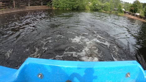 view of the stern of a blue pedal boat moving on the lake in hidden valley holiday park, rathdrum, wicklow, ireland - fisheye shot