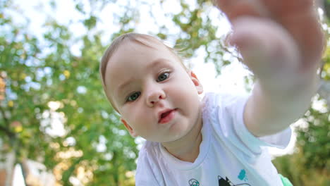 lovely caucasian child with sweet cheeks looking at camera from above. child touching the lens with interest. close up. blurred backdrop.
