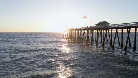 scenic aerial view of couple walking on pier at sunset with flag waving in the breeze