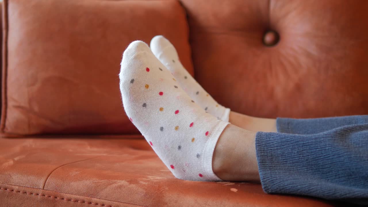 primer plano de los pies en calcetines de puntos polka descansando en un sofá
