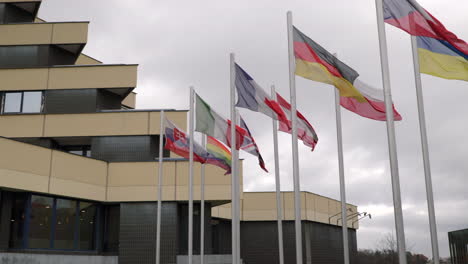 banderas nacionales en el viento frente a un edificio de hotel en un día nublado