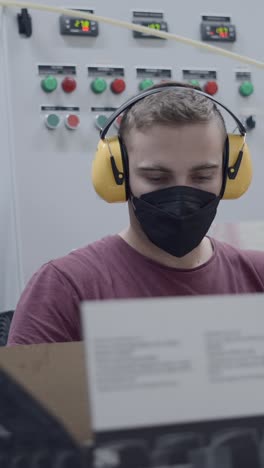 worker operating industrial control panel with ppe