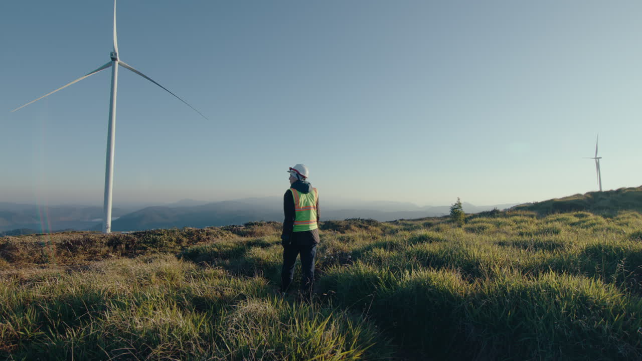 Female Engineer Walking Through Field at Wind Power Plant