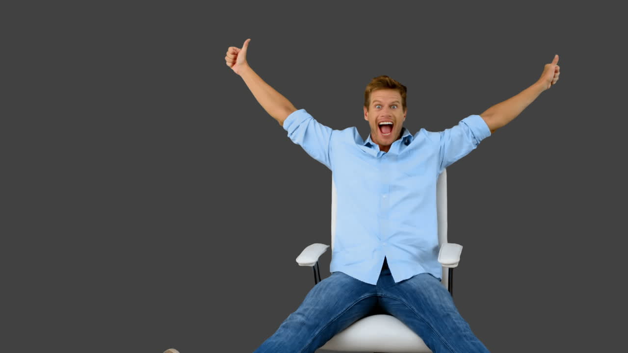 Man on swivel chair giving thumbs up on grey screen