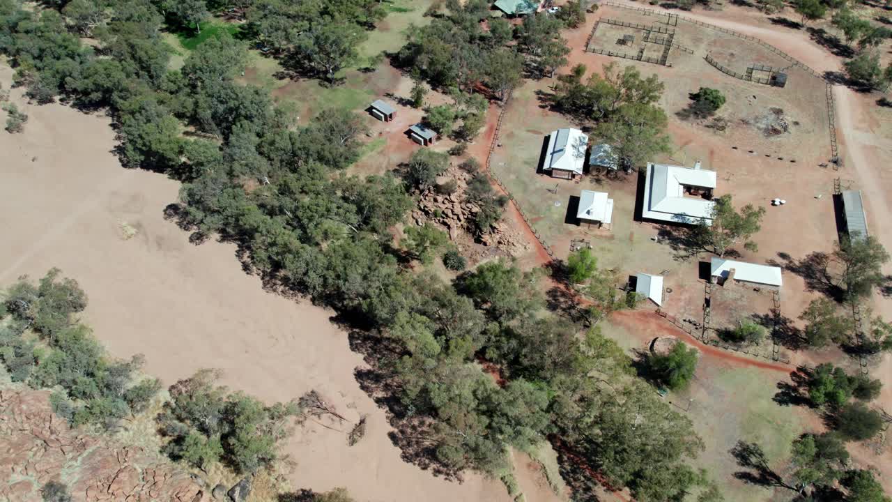 Reversing aerial footage of the Alice Springs Telegraph Station Historical Reserve, panning up to the town of Alice Springs, Mparntwe, Northern Territory, Australia. August 2022.