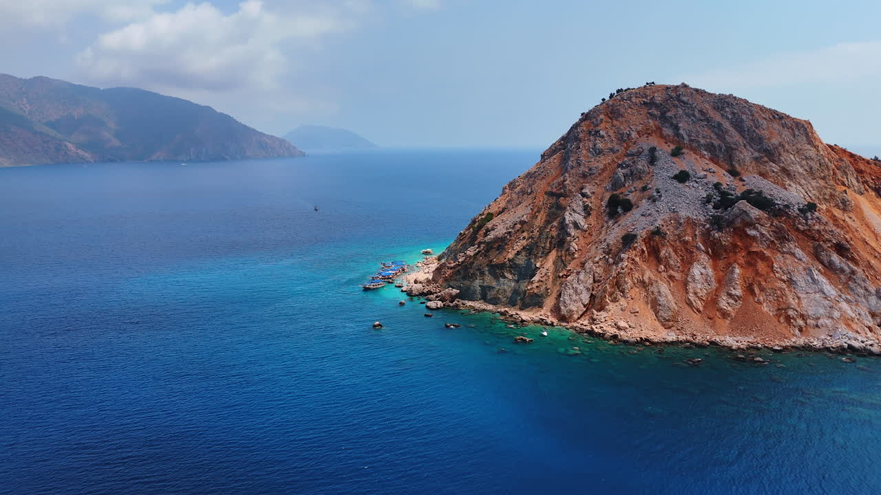 Bare rocky island with unapproachable slopes. Few boats stand on the anchor near the Suluada island in the Mediterranean of Turkey. Aerial view