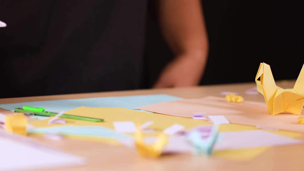 Close-up shot of hands carefully folding a white paper airplane on a wooden crafting table