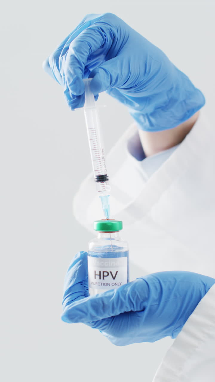video vertical de las manos de un médico caucásico preparando la vacuna contra el hpv, con espacio para copiar