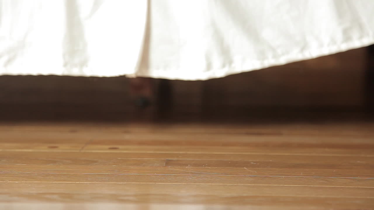 자고 있는 남자가 아침에 일어나 침대에서 일어나 맨발로 바닥을 짚고 있다