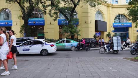 pedestrians walking, cars and motorcycles parked