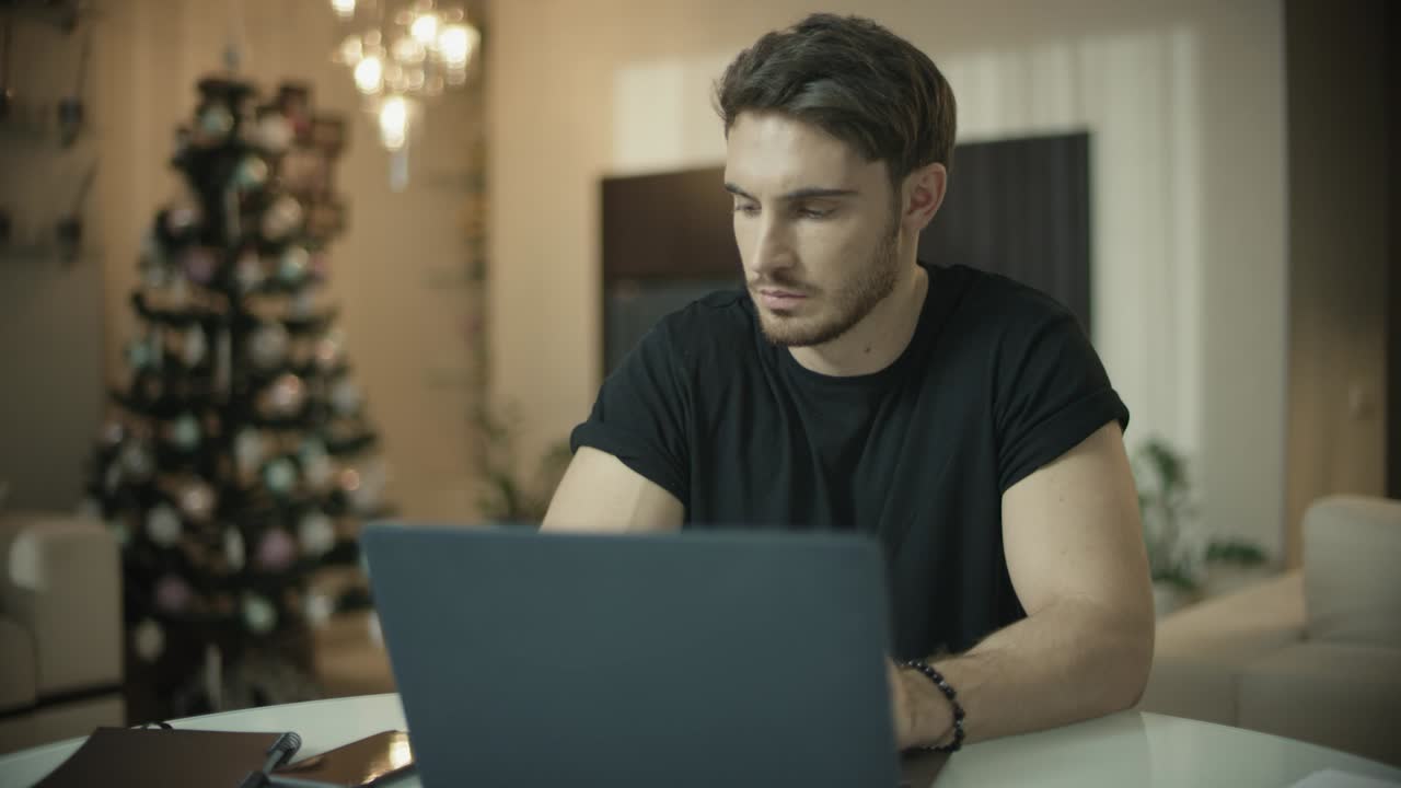 Serious man talking phone at christmas home. Male guy working on computer desk
