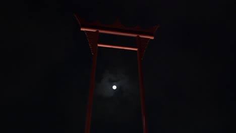 un videoclip de 4k de una súper luna que pasa detrás del columpio gigante, bangkok, tailandia