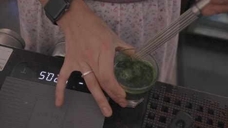 mujer revolviendo café matcha en la cafetería