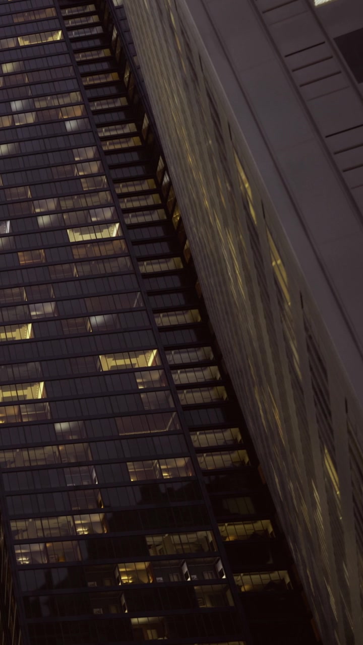 City buildings light up at night with reflections and dark surroundings