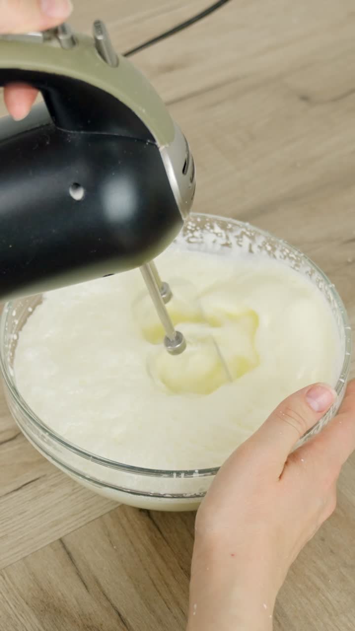 Whisking cream in a glass bowl with an electric mixer to create a smooth texture