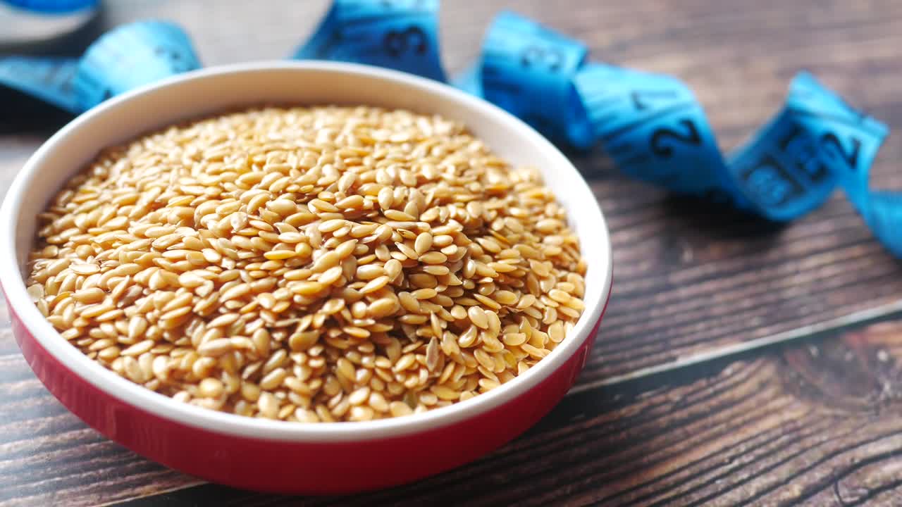 льняные семена в миске с измерительной лентой