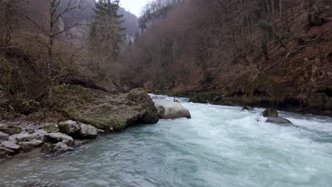 a drone flies over a river canyon gorge on a misty gloomy winters day