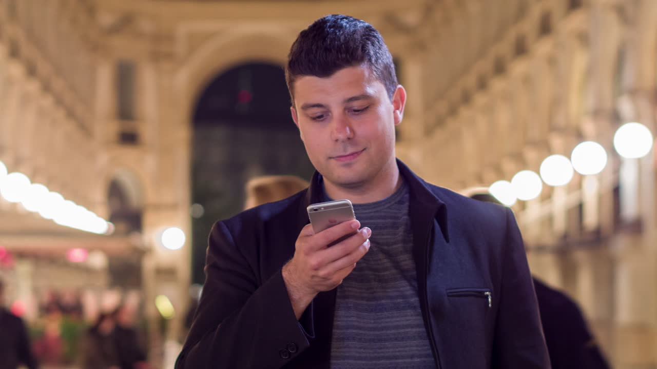 hombre usando un teléfono inteligente por la noche en una ciudad