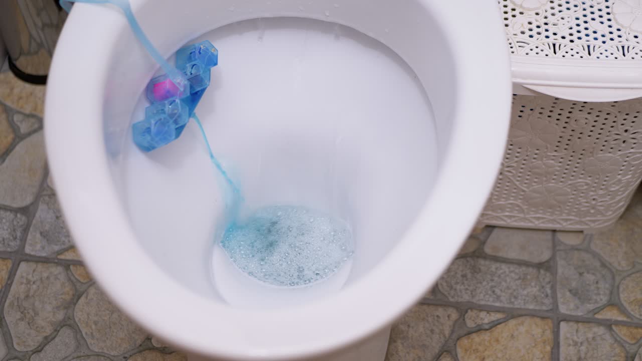 proceso de drenaje de agua en un inodoro blanco con un desinfectante de bolas de refrescante
