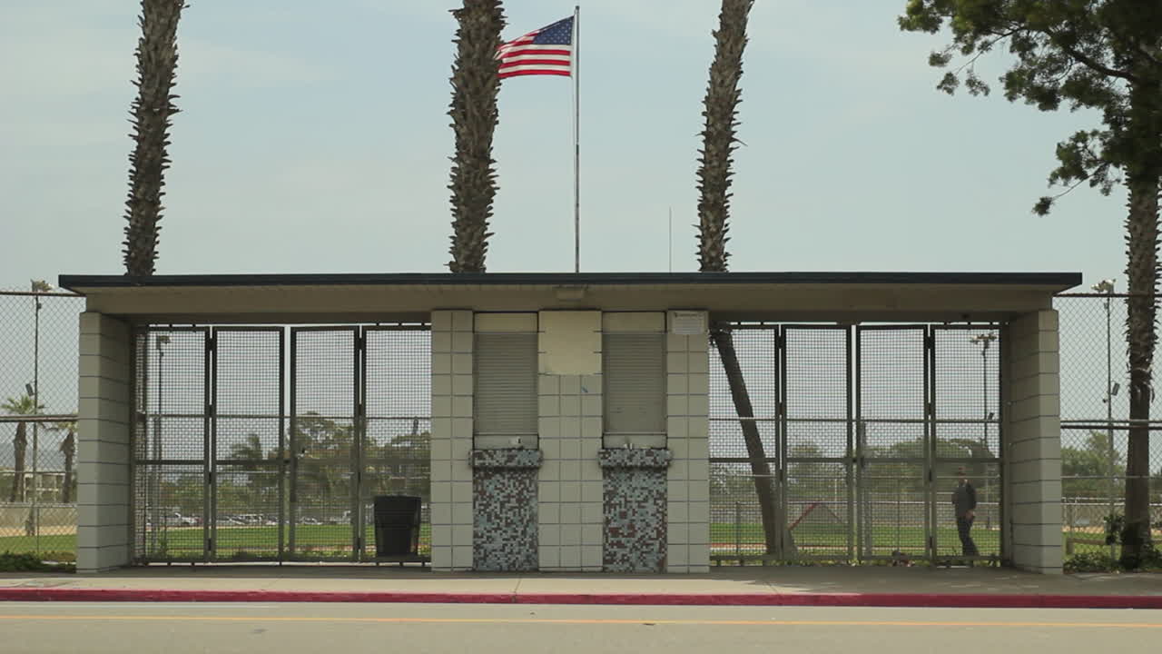 A skater passes under a waving US flag in a quiet urban park