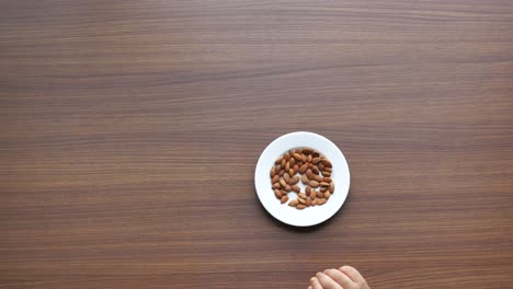 la mano del niño alcanzando las almendras en un plato