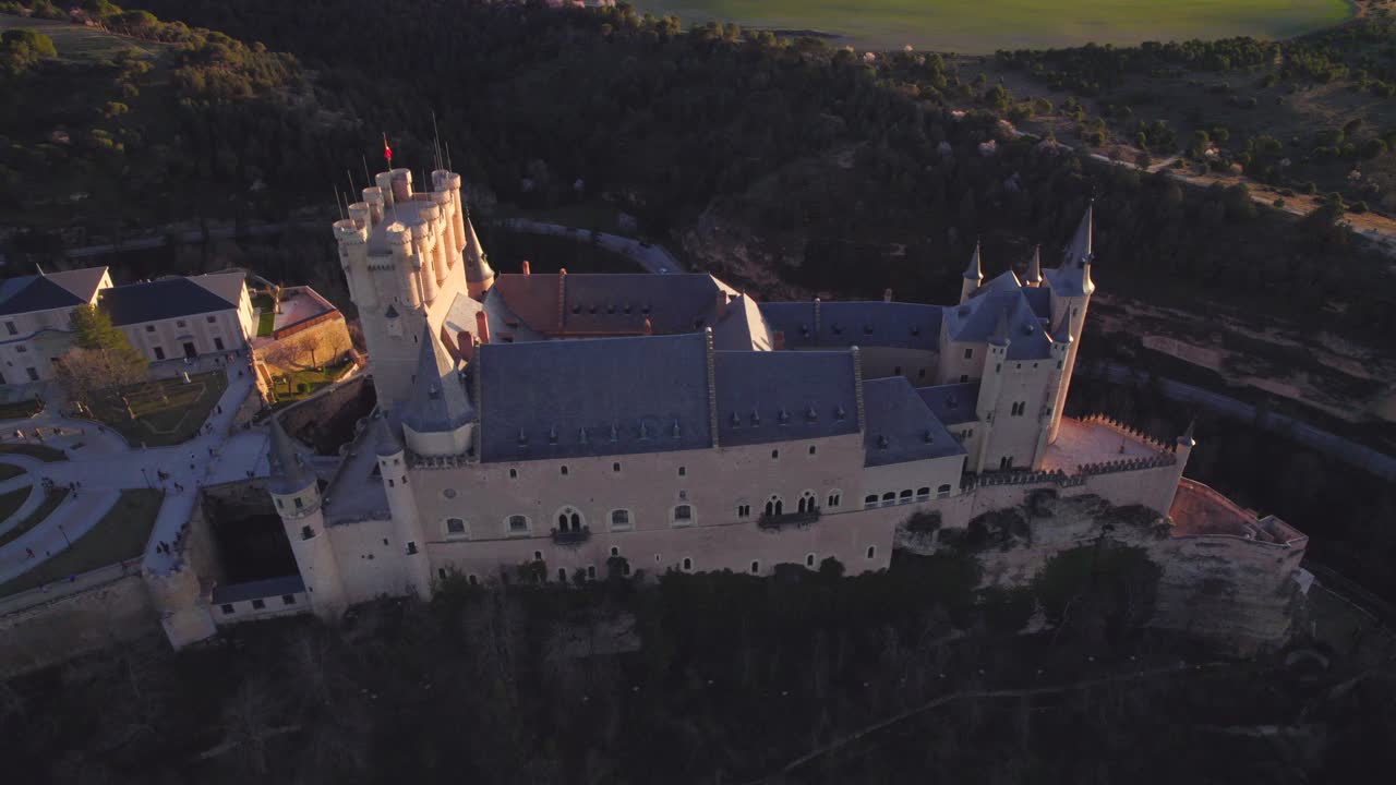 Carrellata aerea all'indietro che rivela l'Alcázar di Segovia al tramonto.