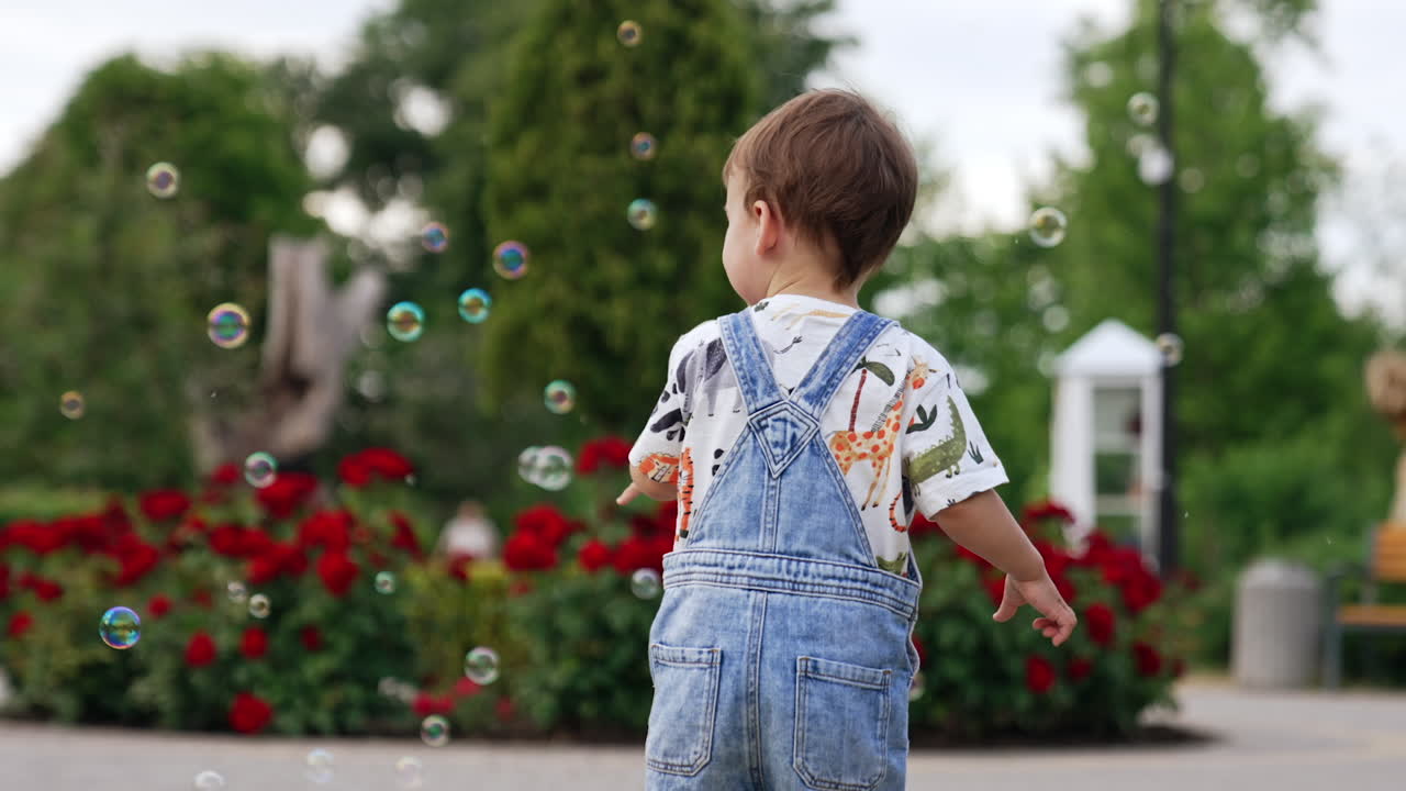 Adorable baby boy catching the soap bubbles. Little toddler on the walk in the park.