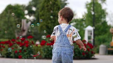 adorable baby boy catching the soap bubbles. little toddler on the walk in the park.