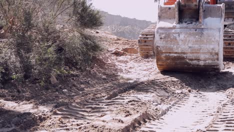 primer plano de la hoja de una excavadora y las vías que trabajan en un sitio de construcción