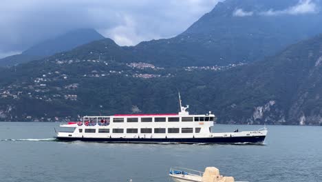 white ferry sails across scenic lake como with mountain backdrop and calm water