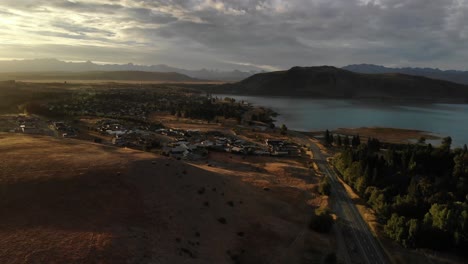 Aerial-View-of-Lake-Tekapo-Township,-New-Zealand-Under-Scenic-Sunset-Sunlight