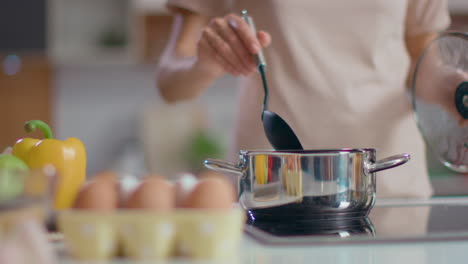 mujer cocinando sopa en la cocina