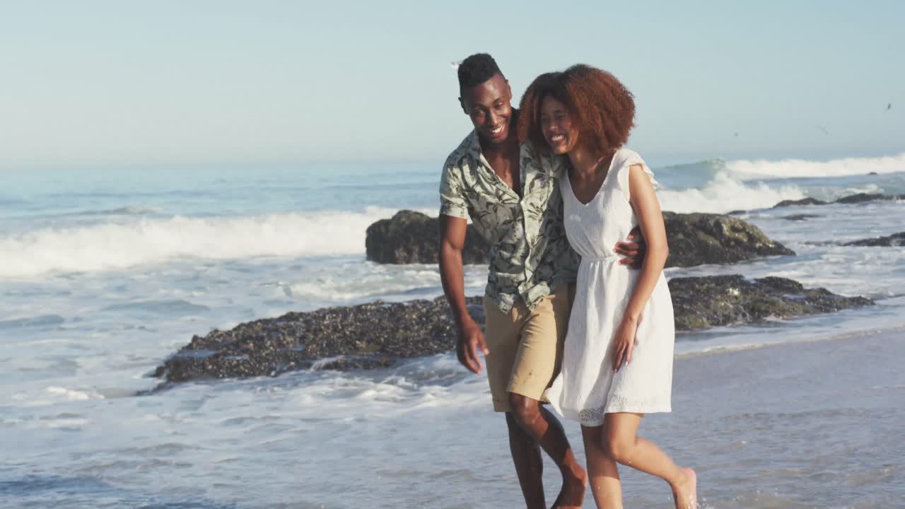African American couple walking seaside and kissing