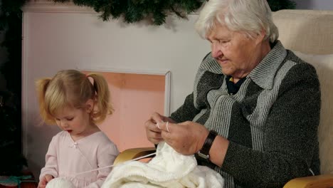 grandmother teaches to knit her granddaughter