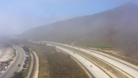 Coche-Recorriendo-Arriba-Y-Abajo-De-La-Autopista-101-Bajo-Una-Fina-Capa-De-Niebla-Que-Se-Filtra-Desde-El-Océano