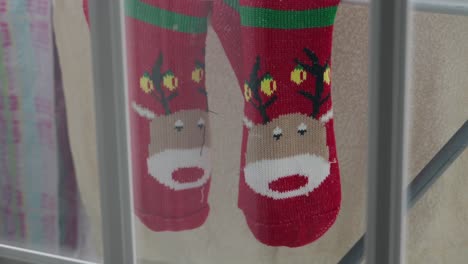 red christmas socks with reindeer hang drying indoors on metal rack
