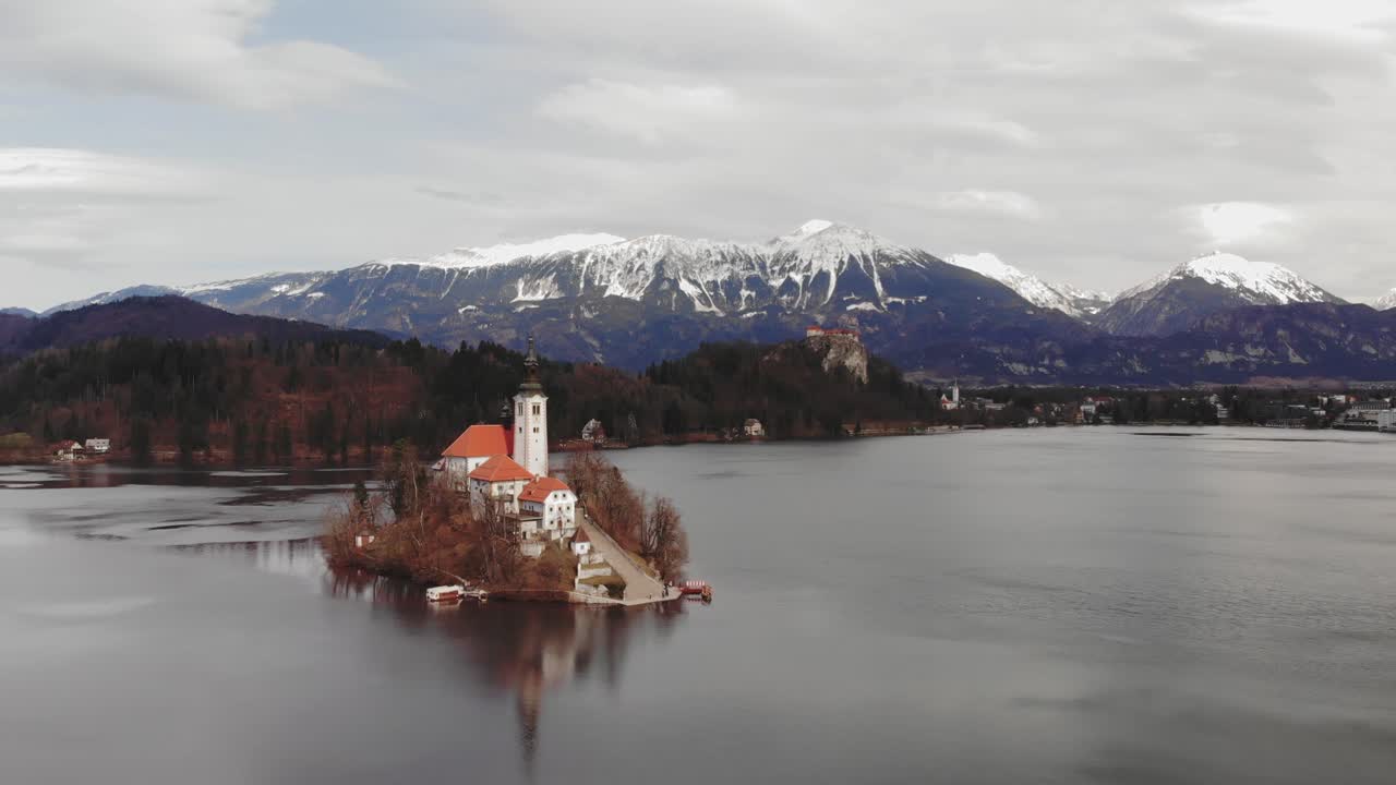 Luchtfoto van een klein eiland midden in een meer met een geïsoleerde kerk en berglandschap op de achtergrond. Meer van Bled, Slovenië