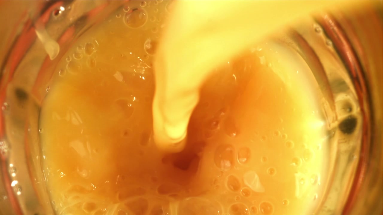 Succo d'arancia vivace versato in un bicchiere trasparente con bollicine.