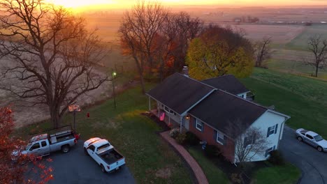 aerial establishing shot of one story home in usa with american flag at beautiful colorful sunrise