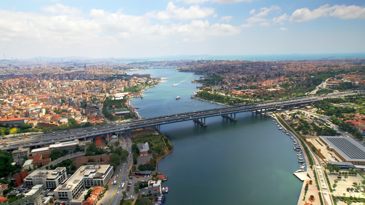 Aerial drone view of Istanbul, Turkey. Halic Bridge with multiple moving cars, multiple residential buildings on the both sides of the Golden Horn waterway, greenery, downtown on the background