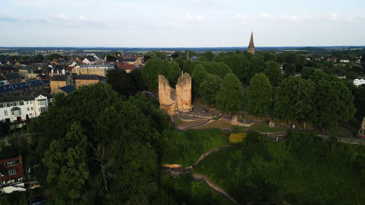 Slow drone paralax around Knaresborough Castle ruins, that are rich in history sat on the top of the hill at sunset surrounded by the new townhouses of the town.Small park, trees surround the castle