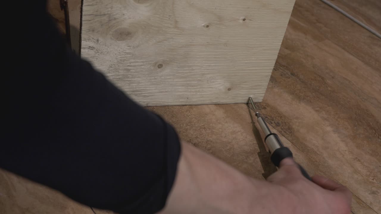 tornillo de conducción de la mano humana en una tabla de madera - toma de primer plano