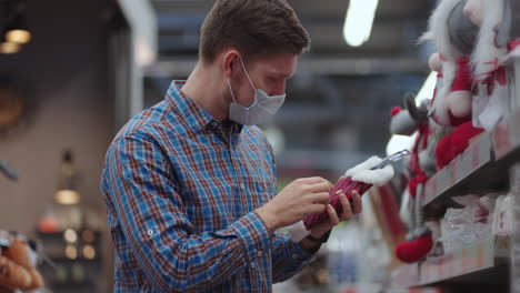 a man in a protective mask in a jewelry store and garlands with toys for christmas trees and at home. christmas garlands and decor